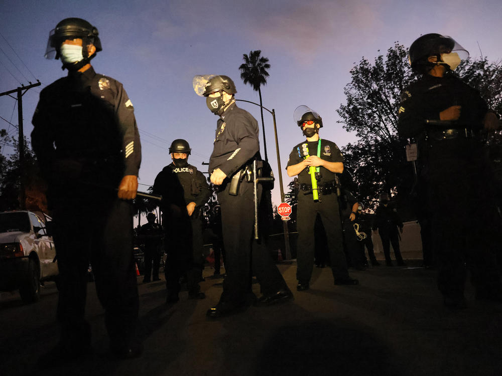 Los Angeles Police Department officers block the street near Echo Park Lake as protesters demonstrate against the removal of a homeless encampment on March 25, 2021, in Los Angeles. Officials asked people living in tents at the park to leave. Police detained 16 journalists reporting on the night's events, arresting two and shooting two others with rubber bullets.