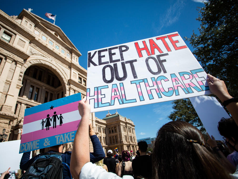 Demonstrators hold signs in support of transgender youth at the Texas State Capitol.