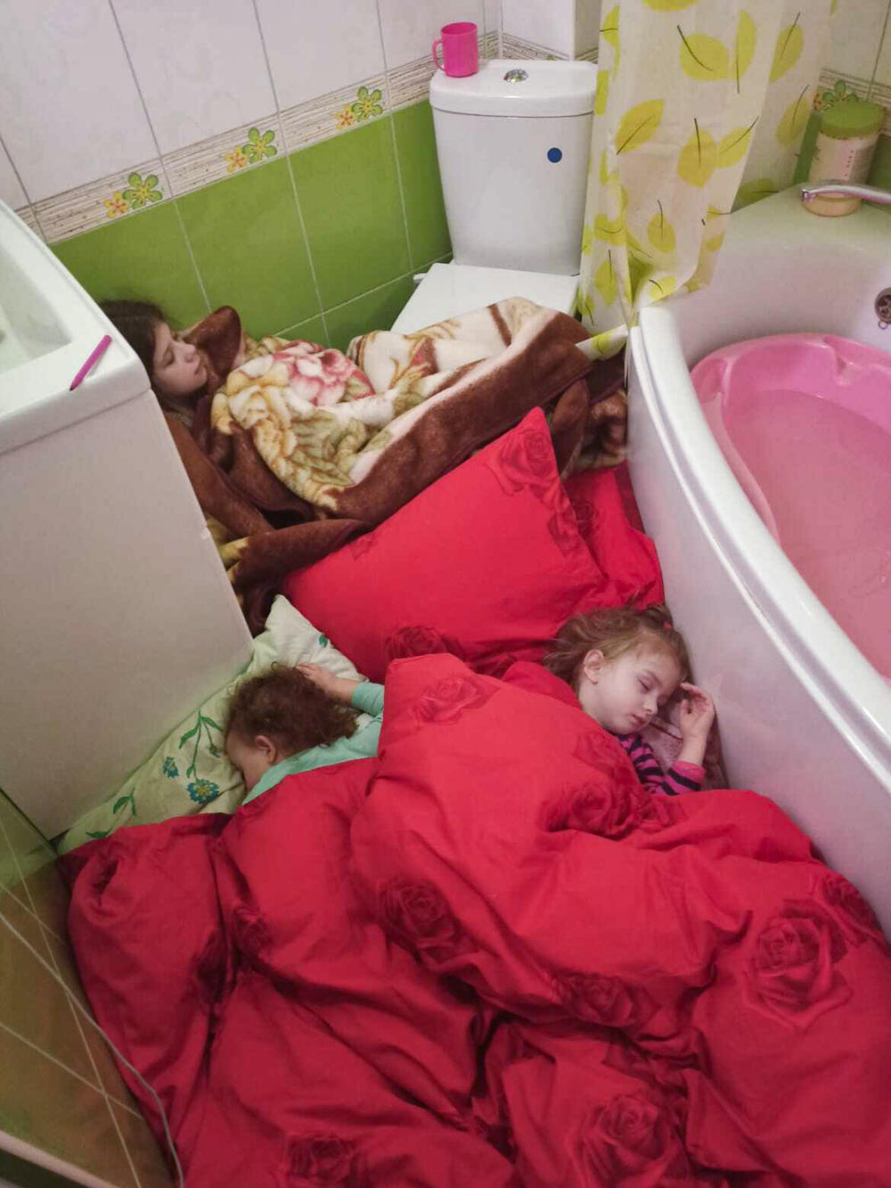 Olha Konstantynovska's three daughters, afraid of an air attack, sleep in their apartment bathroom in Kharkiv. After an explosion down the street, the TB doctor and her family fled.