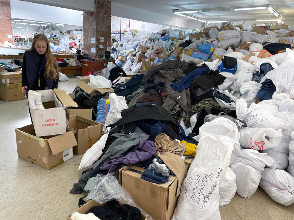 Nastia Stefanovich, a volunteer at the distribution center in Lviv for goods donated for Ukrainians in need, points out the piles of clothes that have been arriving.