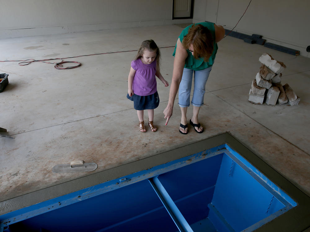 A woman shows her granddaughter the newly installed tornado shelter in the floor of the garage in 2014 in Moore, Okla.