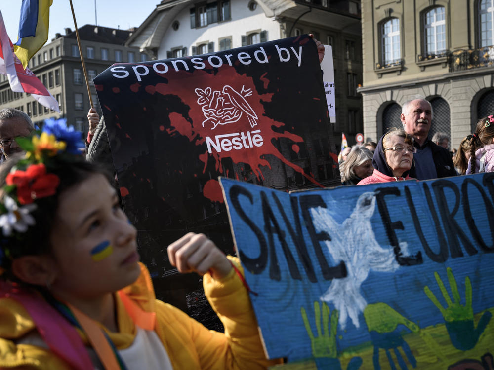 Protesters hold a banner calling out Swiss food giant Nestlé during a demonstration against the Russian invasion of Ukraine next to the Swiss House of Parliament in Bern on Saturday. The company faced criticism in recent days for continuing to do busines in Russia.