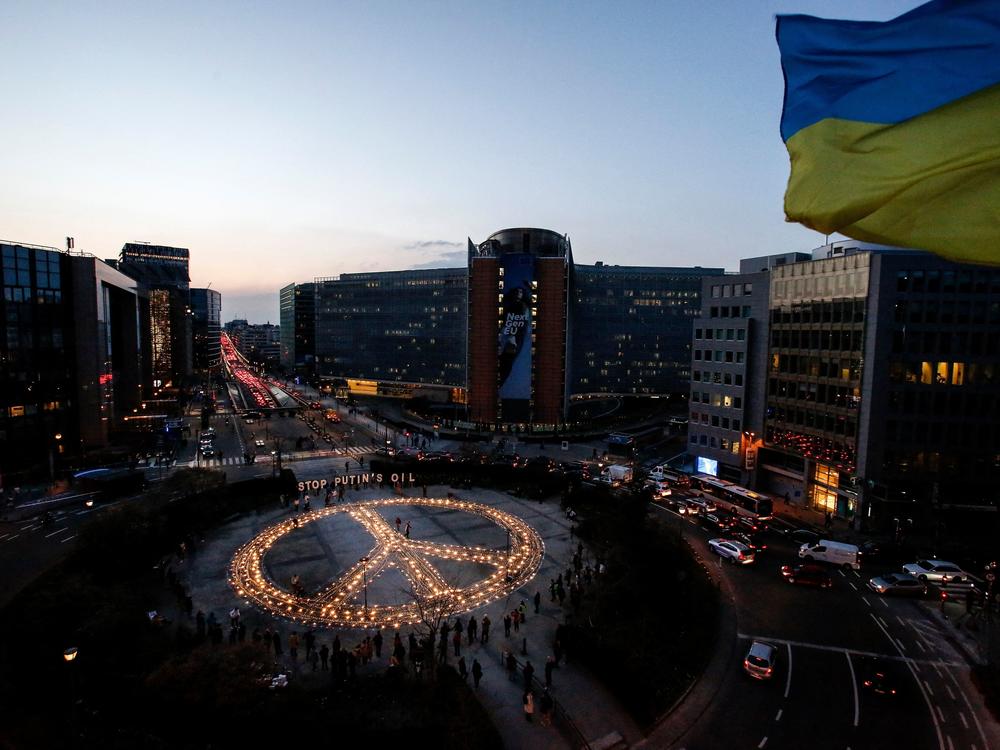 Demonstrators stand around a peace sign during a vigil for Ukraine near the European Union headquarters in Brussels on Tuesday. Activists are calling on EU leaders to impose a full ban on Russian fuel.