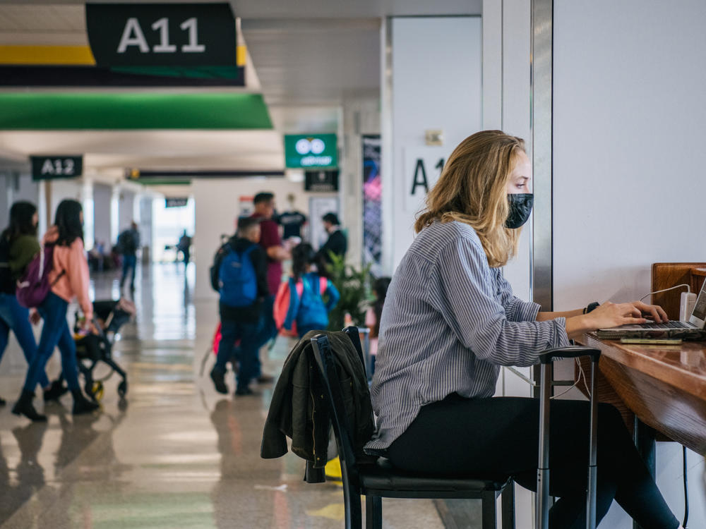 The CEOs of the major U.S. airlines have called on President Biden to end the federal mask mandate for public transportation. Here, a traveler works on a laptop computer at George Bush Intercontinental Airport in Houston on Dec. 3.