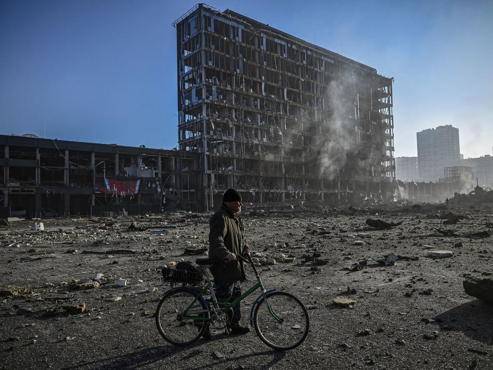 A man with his bicycle walks between debris outside the destroyed Retroville shopping mall in a residential district, after a Russian attack on the Ukrainian capital of Kyiv on Monday.