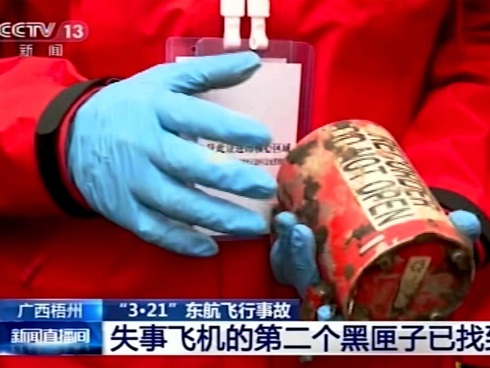 In this image taken from video footage run by China's CCTV, a search and rescue worker holds the second orange-colored 