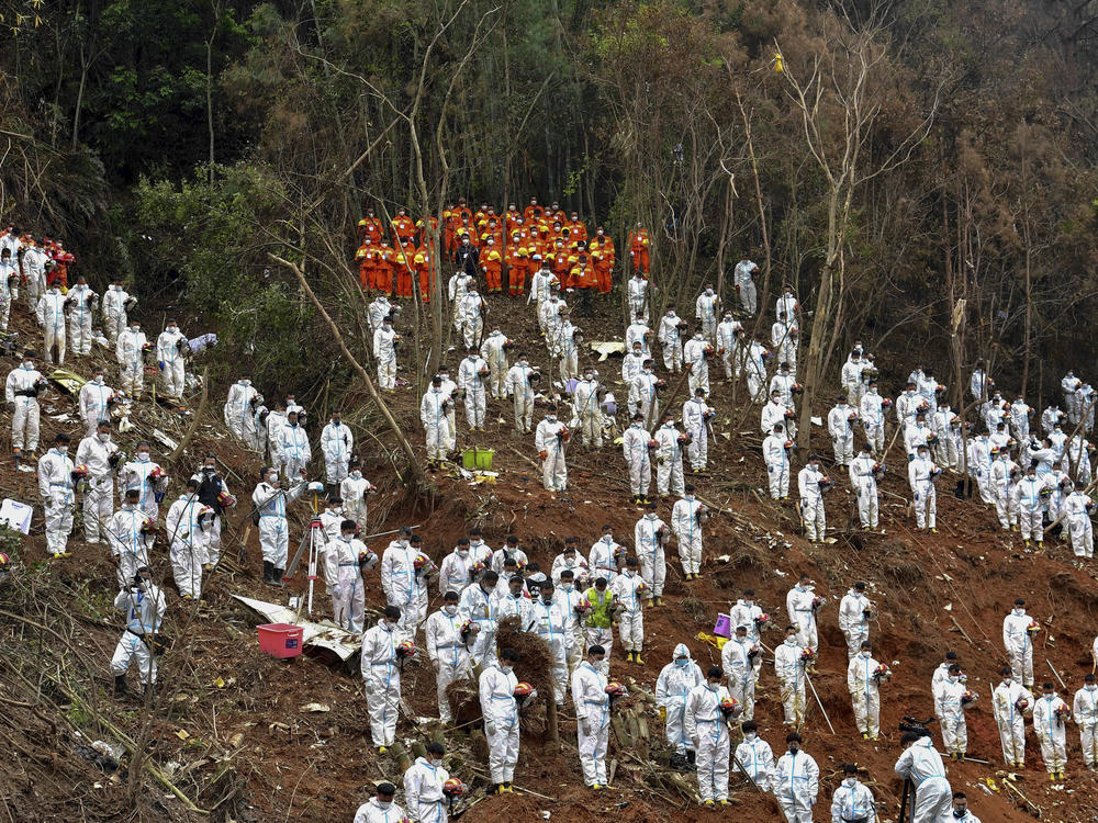 Search and rescue workers pause for a moment of silence for the 132 people killed at the China Eastern flight crash site in Tengxian County on March 27, 2022, in southern China's Guangxi Zhuang Autonomous Region.