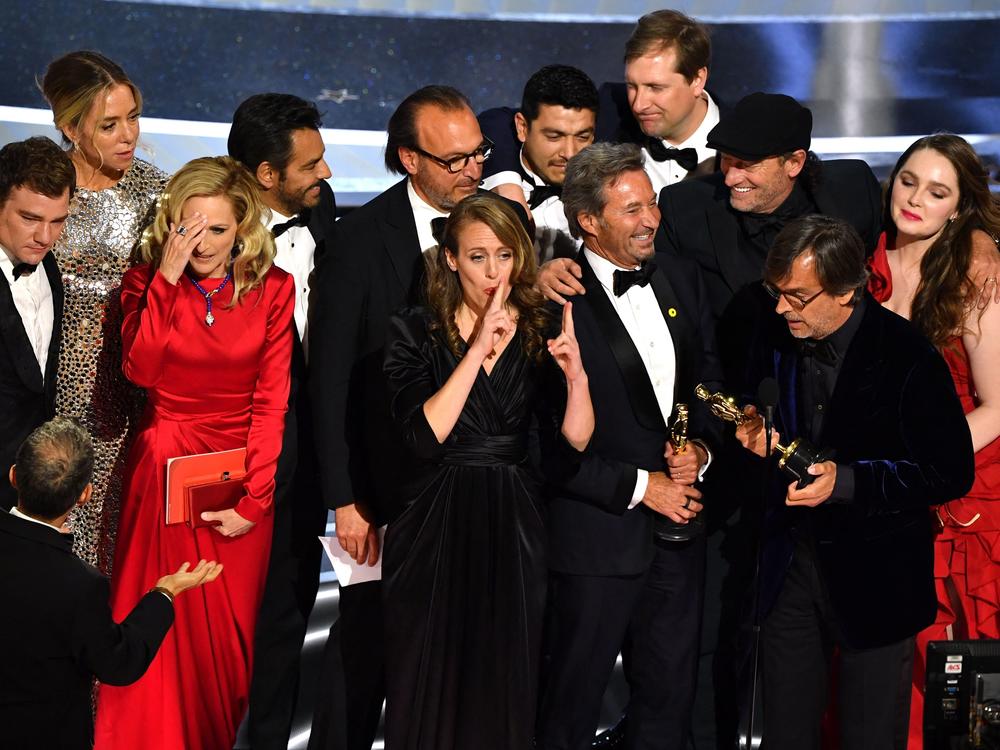 The cast and crew of CODA accept their award onstage.