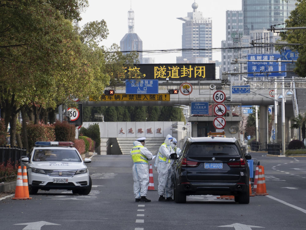 Traffic police wearing protective suits check on a vehicle before an underpass tunnel that has closed following the coronavirus outbreak in Shanghai, China, on Monday.