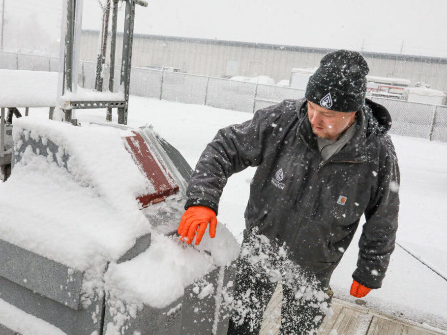 Brandon Hinkhouse, lead operator at the South Platte Renew wastewater treatment, brushes snow away from equipment that collects samples to be tested for coronavirus.