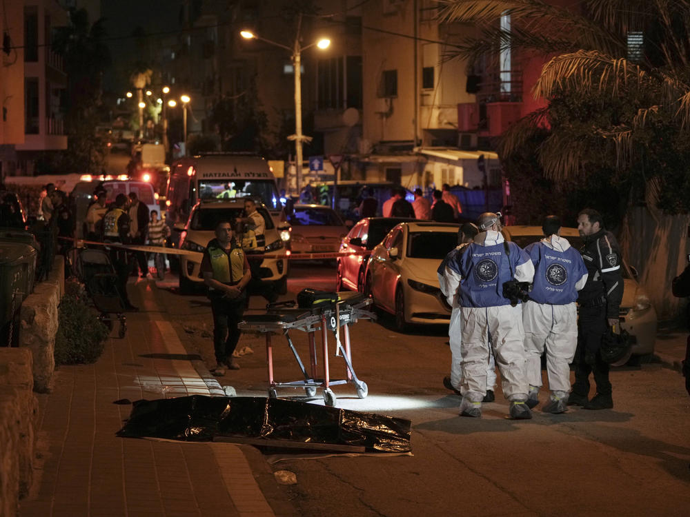 Israeli police work near the covered body of a shooting victim in Bnei Brak, Israel, Tuesday, March 29, 2022. The circumstance of the deadly incident in the city east of Tel Aviv were not immediately clear.