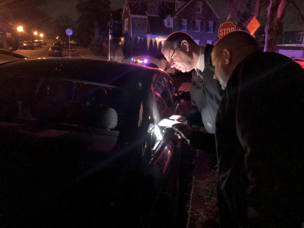 Sgt. Joe Dydak and Lt. Dennis Rosenbaum examine bullet holes in a car. They're part of the Philadelphia Police Department's new citywide team investigating nonfatal shootings.