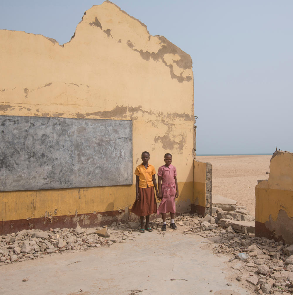 Two schoolgirls stand on the ruins of their school on Feb. 12, 2016, in Dzita, Ghana. One of the Dzita EP Basic School's four compounds was destroyed by coastal erosion during the region's rainy season.