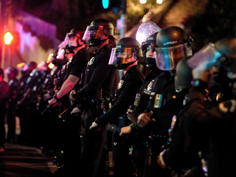Police form a line as activists and supporters of residents of a homeless encampment protest at Echo Park Lake in Los Angeles late on March 24, 2021.