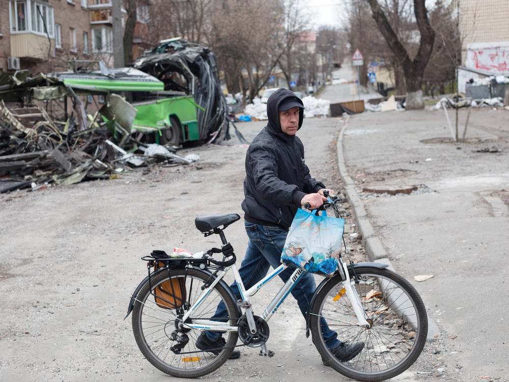 A man with a bicycle walks near a tram which got destroyed by a rocket strike in the area few weeks ago on Monday in Kyiv, Ukraine.