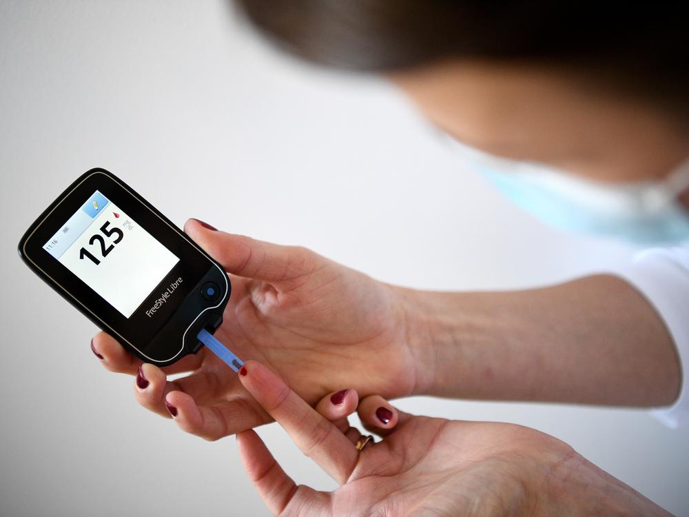 A woman with diabetes uses a glucometer to measure the glycemia in her blood on March 24, 2020.