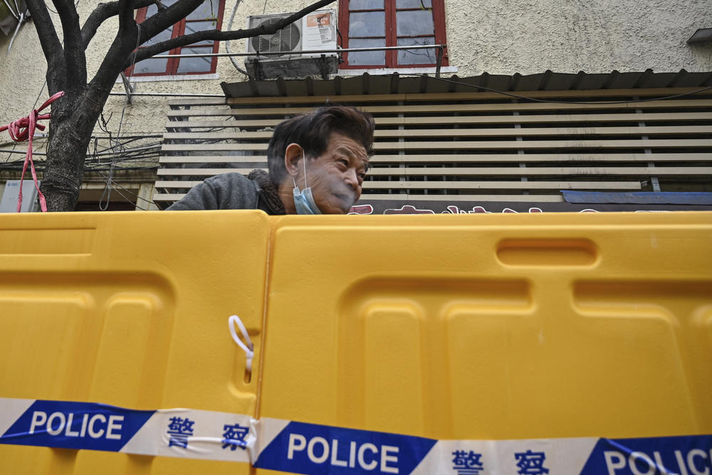 A man stands behind barriers during Shanghai's current COVID lockdown. The speed at which the lockdown was announced left the city's residents scrambling to secure food and supplies.