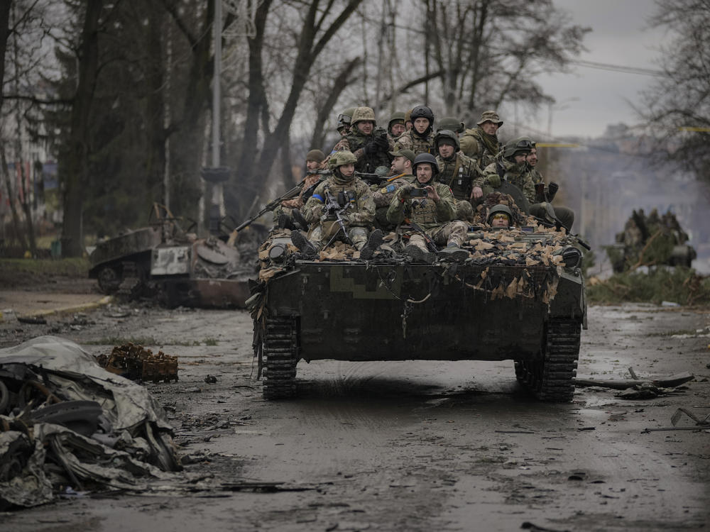 Ukrainian servicemen ride on a fighting vehicle outside Kyiv on Saturday. Russian forces are retreating from the capital's region as they turn their firepower to the south and east.