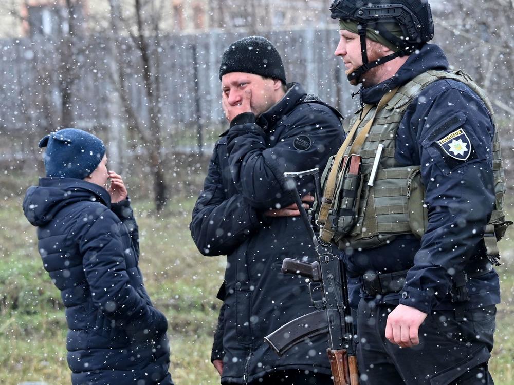 People react as they gather close to a mass grave in the town of Bucha, just northwest of the Ukrainian capital of Kyiv on Sunday.
