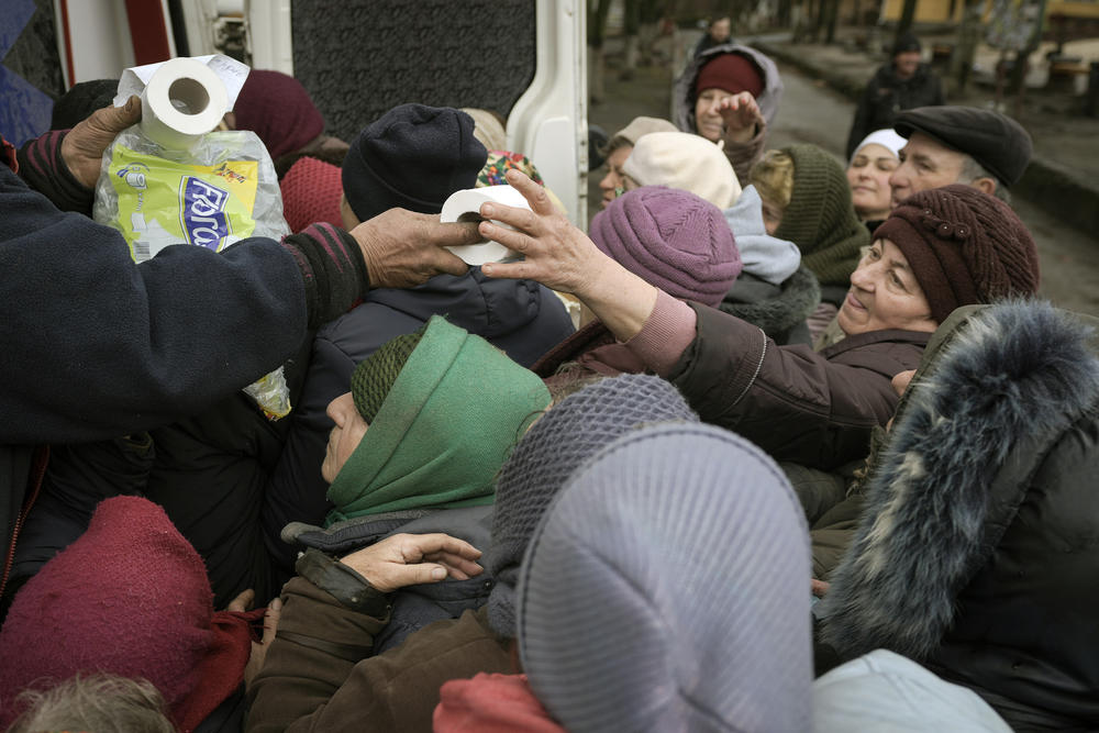 <strong>April 2:</strong> A man distributes toilet paper rolls as people wait for medicine and sanitary supplies after a convoy of military and aid vehicles arrived in the formerly Russian-occupied Kyiv suburb of Bucha.