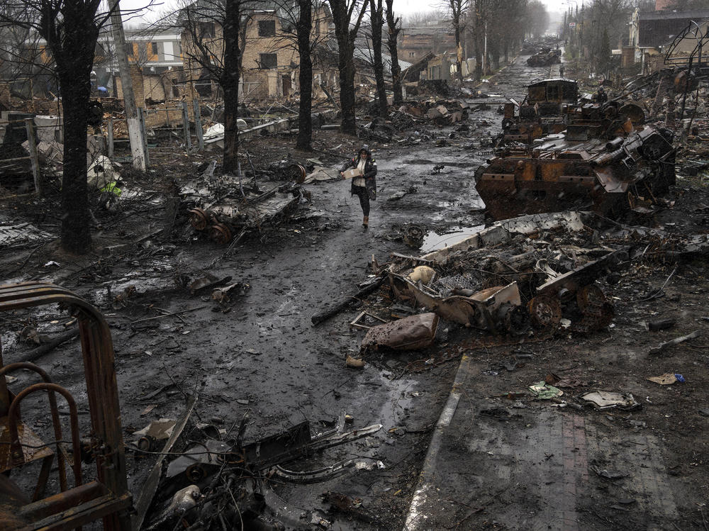 <strong>April 3:</strong> A woman walks amid destroyed Russian tanks in Bucha, on the outskirts of Kyiv.