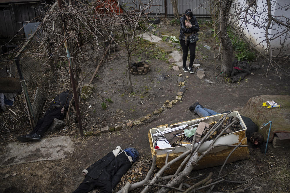 A woman walks with her cat next to the corpses of her husband and brother, killed in Bucha.