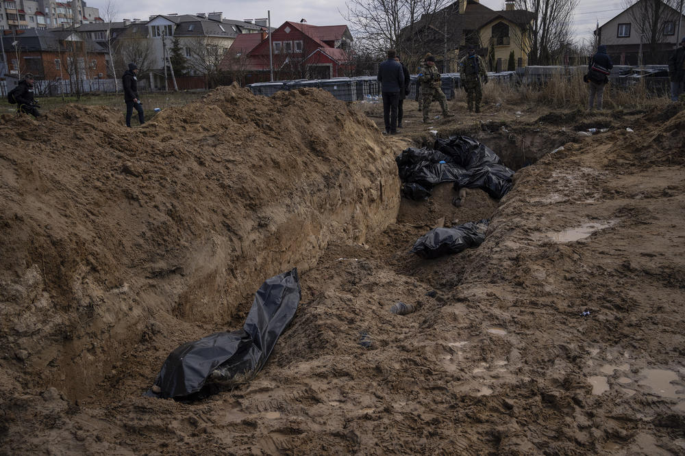 Journalists stand by a mass grave in Bucha on Monday.