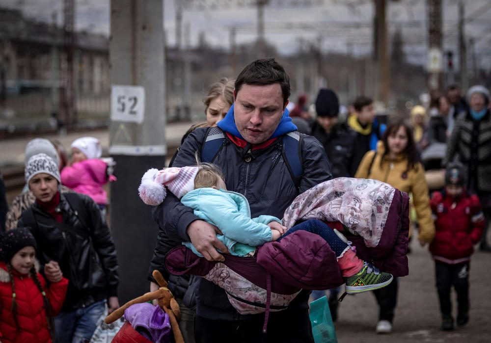<strong>April 4:</strong> A man carries a little girl as he arrives with other families to board a train at Kramatorsk central station as they flee the eastern city of Kramatorsk, in the Donbas region, amid Russia's ongoing invasion of Ukraine.
