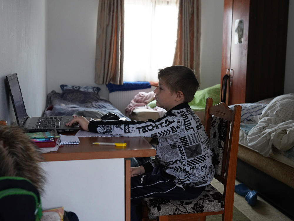 Dima, who fled the war in Ukraine with his mother, attends an online class, at the 