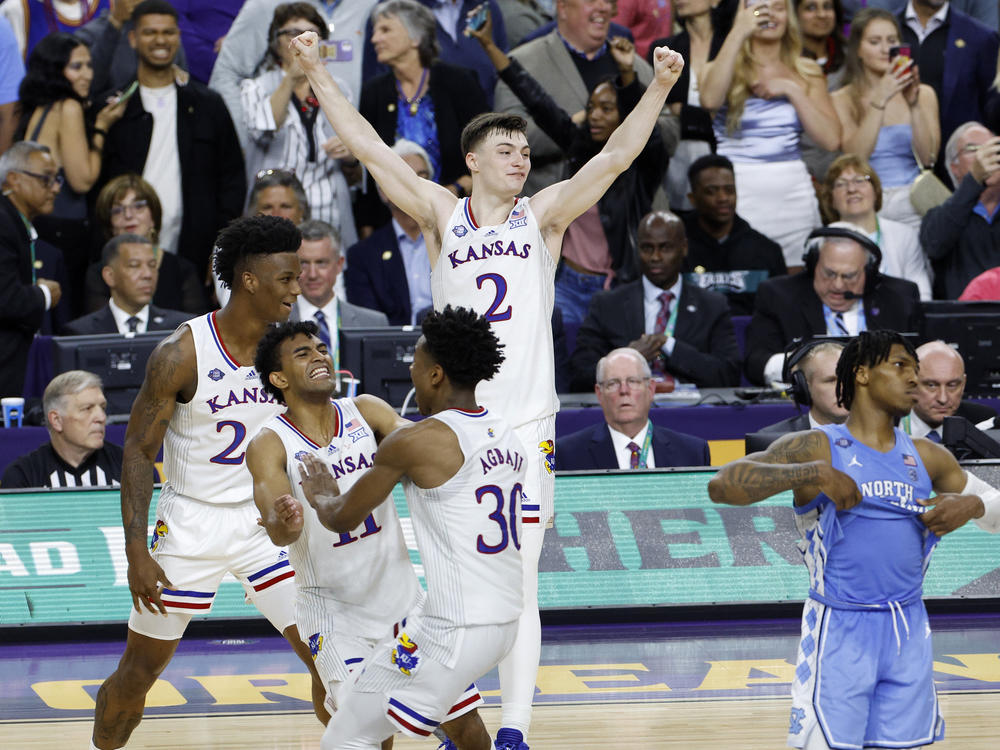 K.J. Adams #24, Remy Martin #11, Ochai Agbaji #30, and Christian Braun #2 of the Kansas Jayhawks celebrate after defeating the North Carolina Tar Heels 72-69 during the 2022 NCAA Men's Basketball Tournament National Championship in New Orleans.