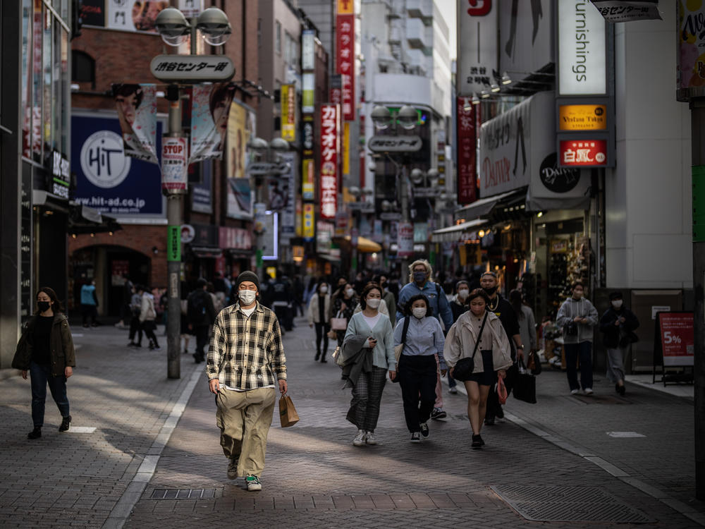 A man wearing a face mask walks along a shopping street on March 25, 2022, in Tokyo.