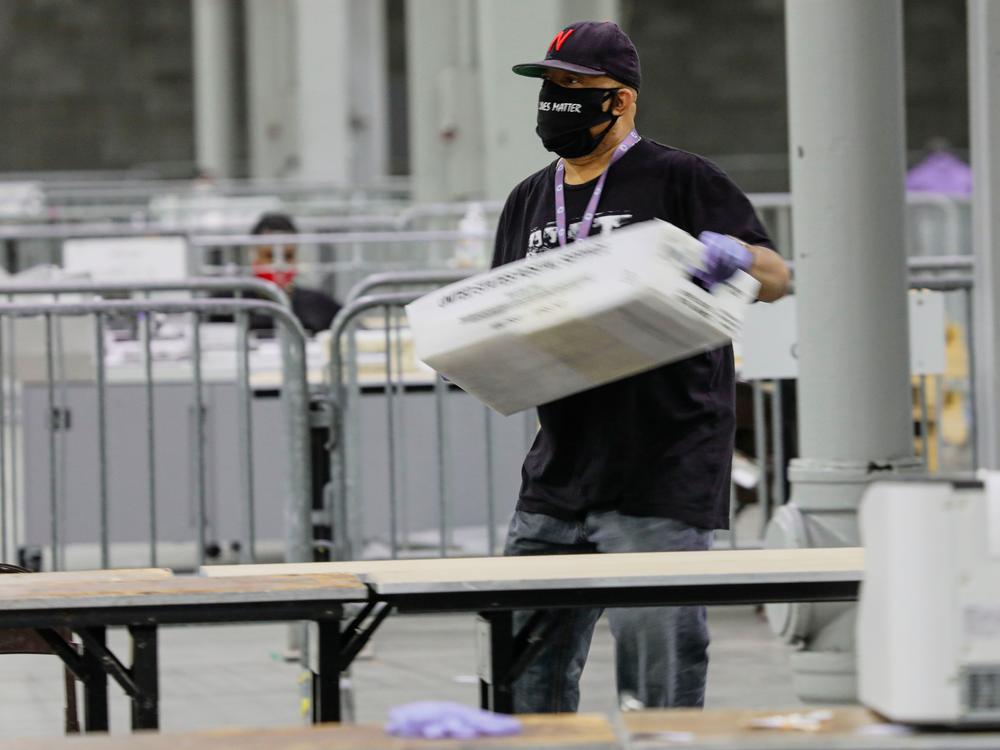 An election worker in Atlanta carries a bin of ballots to be scanned on Jan. 5, 2021, during Georgia's U.S. Senate runoff elections.
