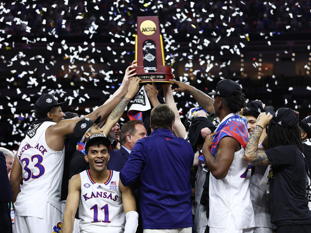 Remy Martin reacts as Kansas Jayhawks players and coaches hold up the National Championship trophy after defeating the North Carolina Tar Heels in the 2022 NCAA Men's Basketball Tournament National Championship on Monday in New Orleans.