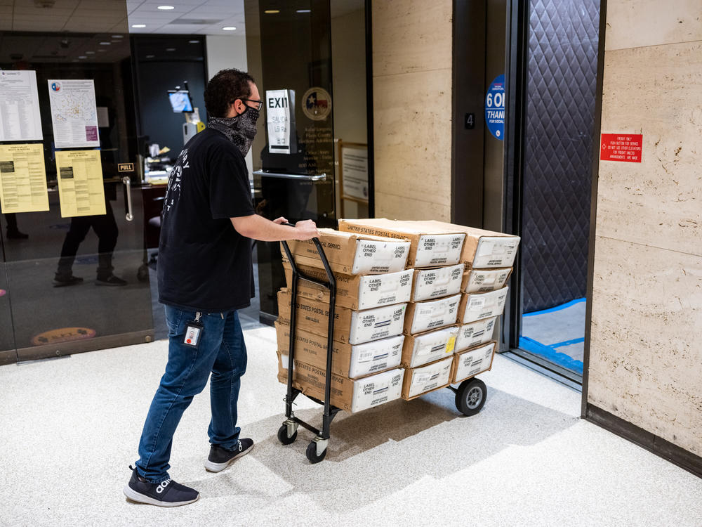 In February, ahead of the Texas statewide primary, Carlos Vanegas at the Harris County Elections Office in Houston pushes a cart with mail-in ballots to be sent to voters. The county ultimately rejected thousands of the mail ballots it received back.