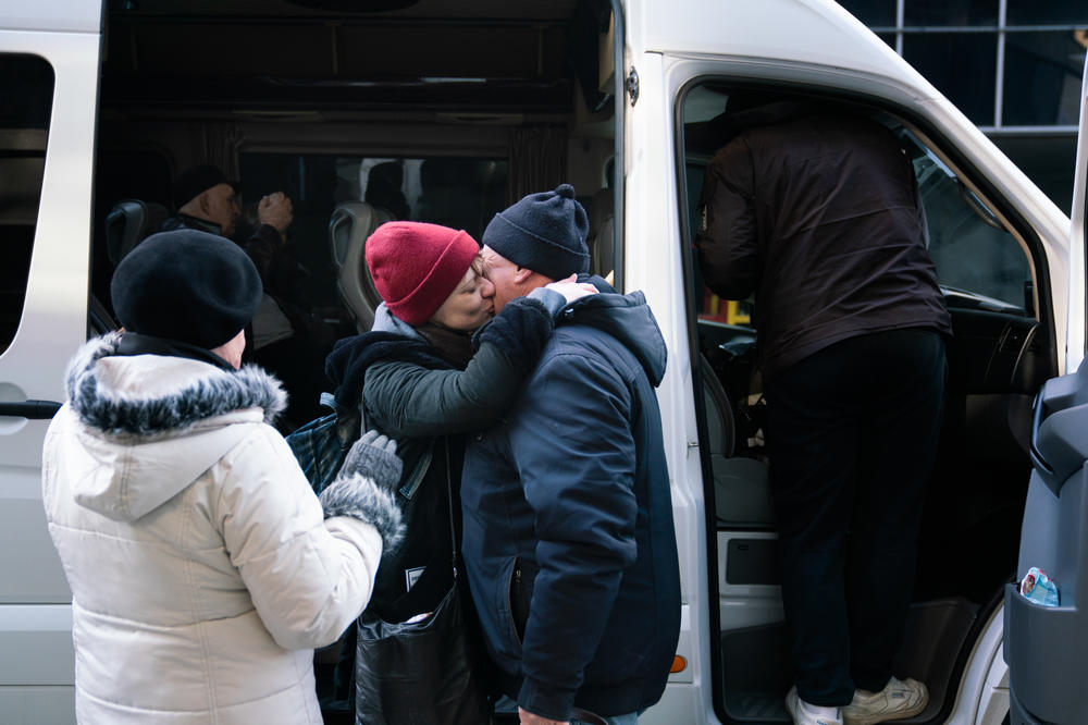 Sergei Kuzmenka (right) says goodbye to his daughter as her mother, Valentina Kuzmenka, watches just moments before the daughter boards the bus to leave Ukraine.