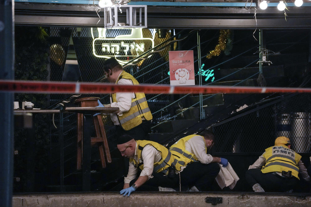 Members of Israeli Zaka Rescue and Recovery team clean blood from the site of a shooting attack In Tel Aviv on Thursday.