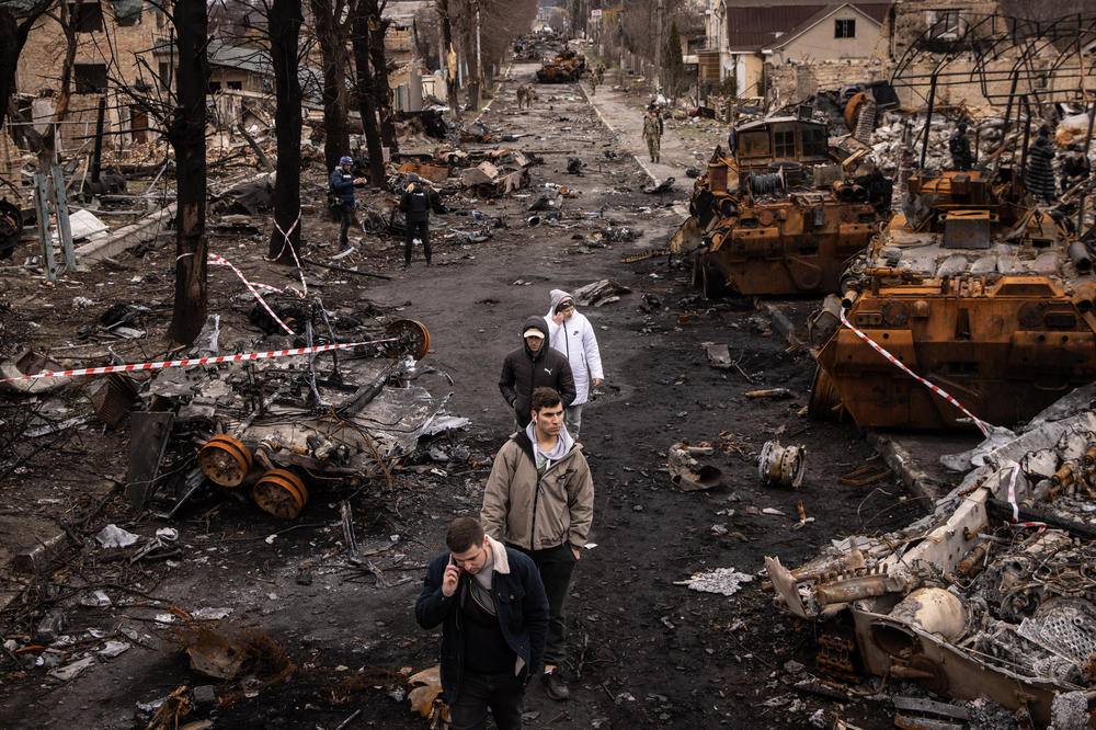 People walk through debris and destroyed Russian military vehicles on a street in Bucha, Ukraine, in April.
