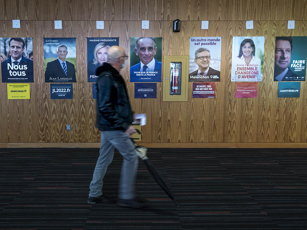 A French voter passes identification posters on his way to vote in the first round of the 2022 French presidential election, in Montreal, Saturday, April 9, 2022.