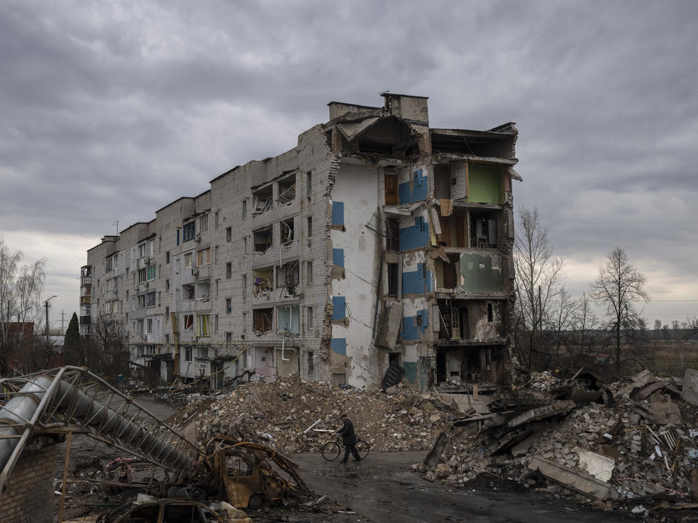 A man with a bicycle walks in front of a destroyed apartment building in the town of Borodyanka, Ukraine, on Saturday, April 9, 2022.