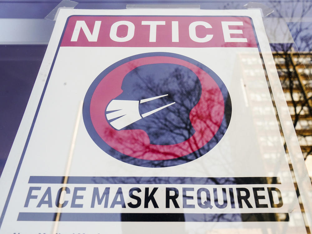A sign requiring masks as a precaution against the spread of the coronavirus is taped on a storefront in Philadelphia on Feb. 16.