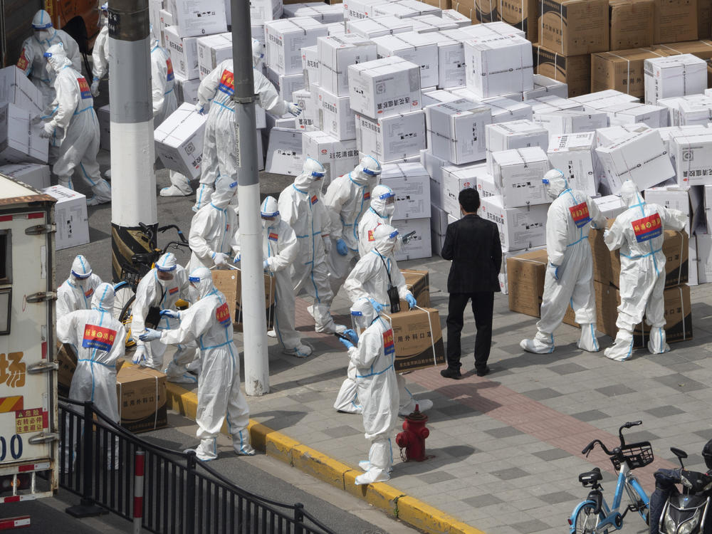 Workers unload supplies including boxes of masks in Shanghai on Sunday, April 10, 2022.