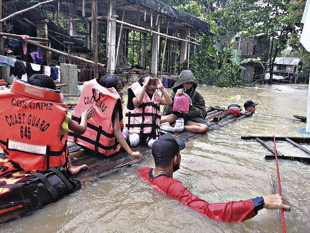 Residents are evacuated by rescuers in a flooded village in Panitan, Panay island, Philippines on Tuesday. Heavy rains caused by a summer tropical depression killed at least a few dozen people in the central and southern Philippines, mostly due to landslides, officials said.