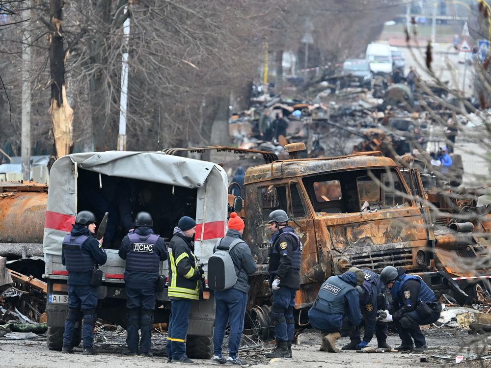 Emergency workers conduct mine-clearing operations among destroyed vehicles on a street of Bucha outside of Kyiv last week.