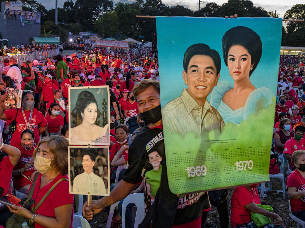 A supporter holds pictures of the late dictator Ferdinand Marcos and his wife Imelda Marcos, as Ferdinand 