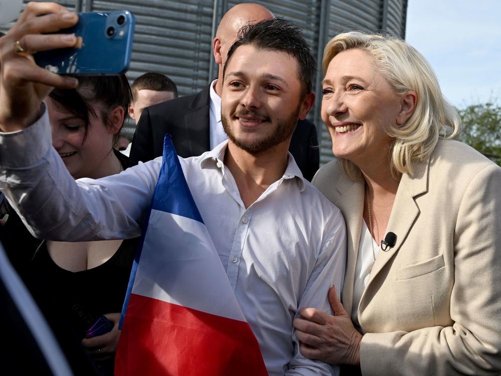 French far-right party Rassemblement National (RN) presidential candidate Marine Le Pen poses for a picture with a supporter holding a French national flag during a visit at a grain farm as part of her campaign for the second round of the French presidential election, on April 11, 2022 in Soucy, Burgundy.