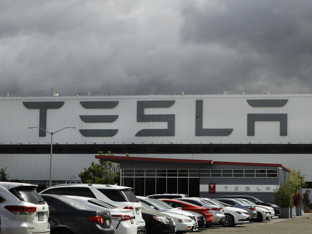 Vehicles are parked outside the Tesla plant in Fremont, Calif., on May 12, 2020. A federal judge has slashed the award to a Black former contract worker over claims that he was subjected to racial discrimination at the factory.