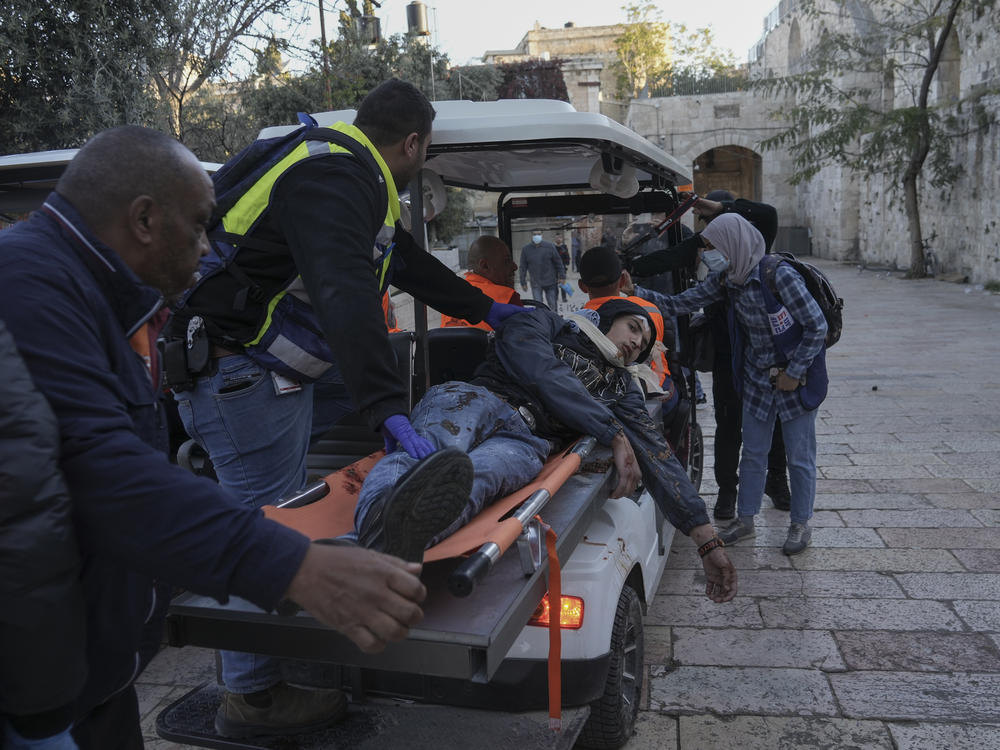 Palestinians evacuate a wounded man during clashes with Israeli security forces, outside Al Aqsa Mosque compound in Jerusalem's Old City Friday, April 15, 2022.