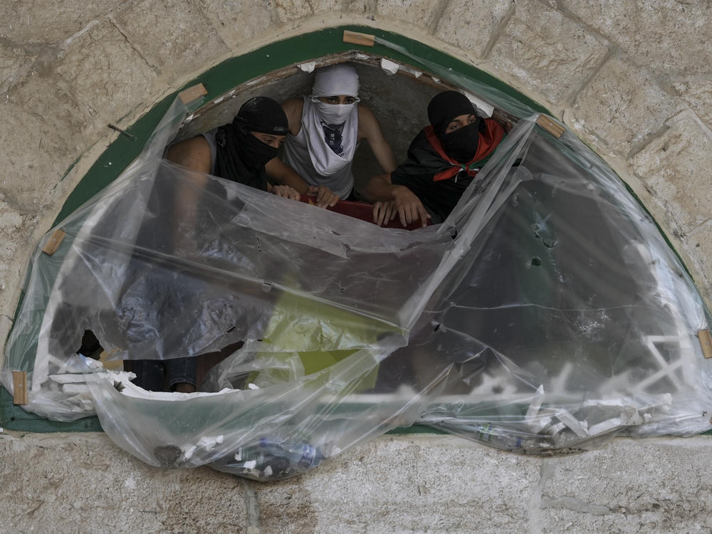 Masked Palestinians take position during clash with Israeli security forces at the Al Aqsa Mosque compound in Jerusalem's Old City Friday, April 15, 2022.