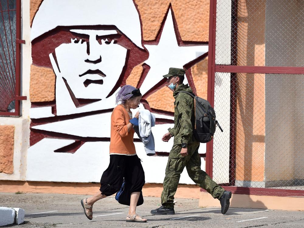 A soldier and a woman walk past the headquarters for Russian troops in September 2021 in the town of Tiraspol, in Trans-Dniester, a pro-Russian region that declared independence from Moldova but is internationally unrecognized. Russia has stationed 1,500 soldiers in the area.