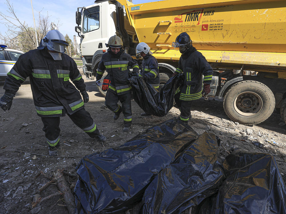 Crews carry body bags as they search for remains and remove debris in the Borodyanka area outside Ukraine's capital of Kyiv on Friday.